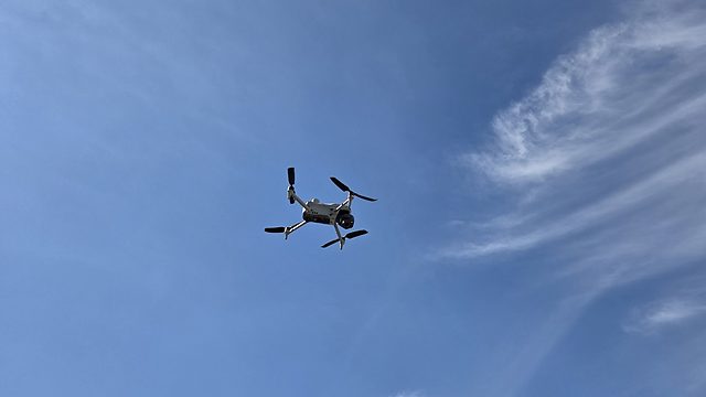 Drohne im Flug vor blauem Himmel